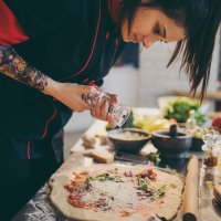 foto kokk som krydrer pizza