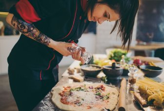 foto kokk som krydrer pizza