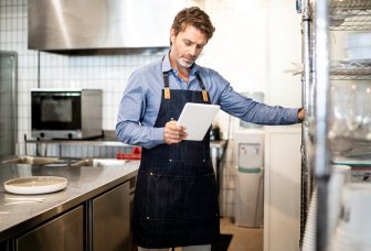 foto mann på kjøkken leser på en ipad